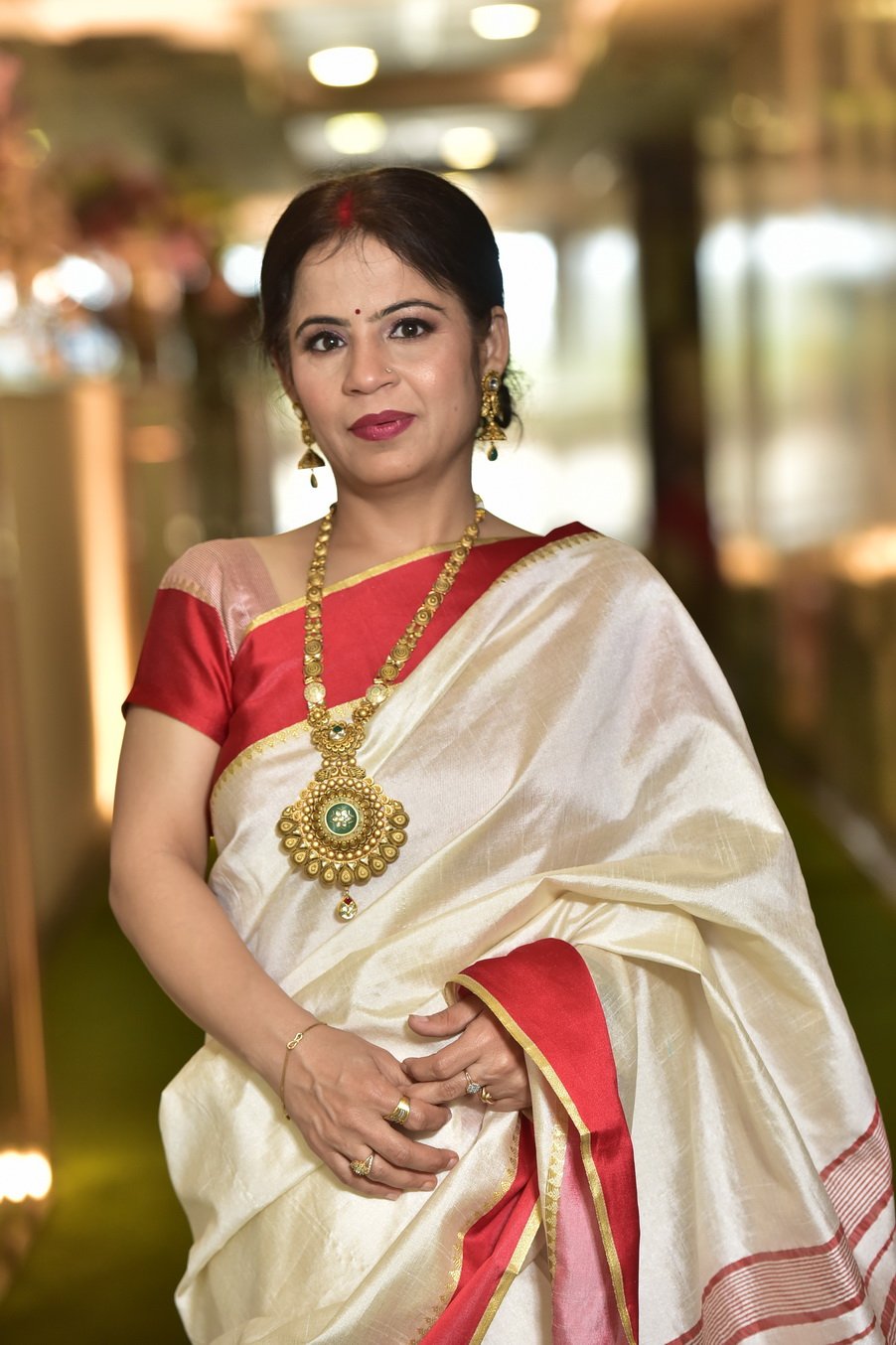 Dr. Meenakshi Girdhar in a white and red saree